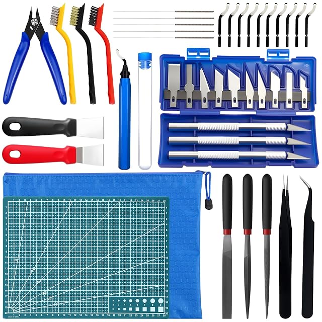 Ausgelegtes Set: Seitenschneider, drei Bürsten, Nadeln, Entgrater und zehn Klingen, zwei Schaber, ein Messerset in blauem Etui, eine Schneidematte, eine Reißverschlusstasche, drei Feilen und eine Pinzette