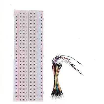 Langes weißes lötfreies Breadboard mit roten und blauen Schienenlinien an beiden Rändern neben einem Bündel flexibler Jumperkabel