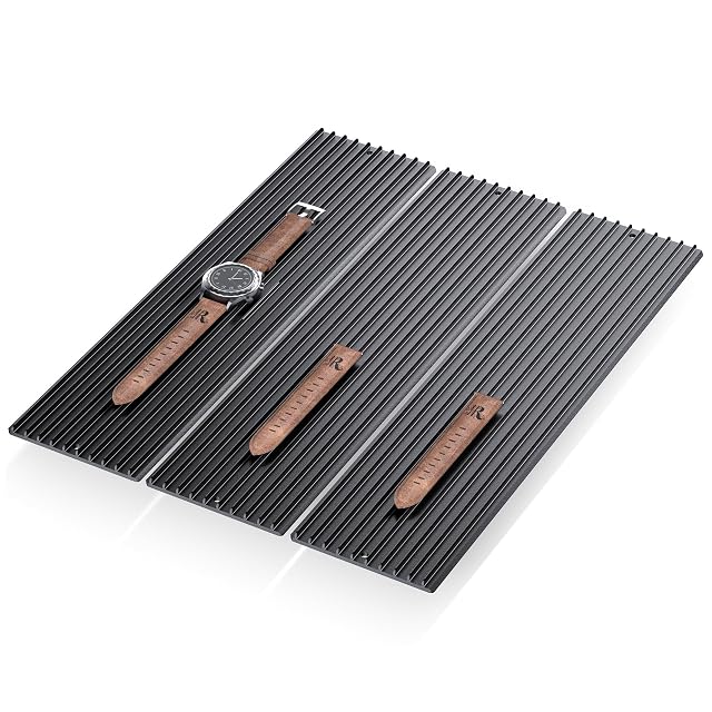 Drei schwarze gerippte Aluminium-Lamellenmodule nebeneinander, mit einer Uhr und Lederarmbändern darauf