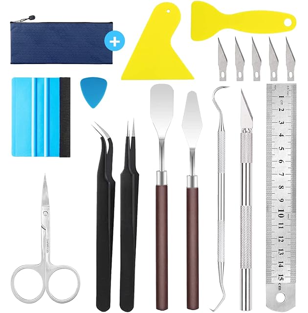 Ausgelegte Werkzeuge: Reißverschlusstasche, zwei gelbe Schaber, ein Rakel mit Filzkante, eine Nadel, fünf Klingen, Pinzette, zwei Spatel, Haken, Bastelmesser, Stahllineal und Schere